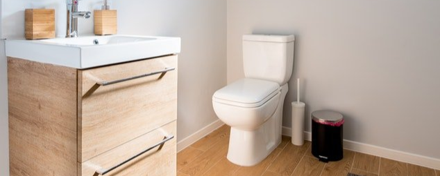 A bathroom with a toilet , sink and trash can.