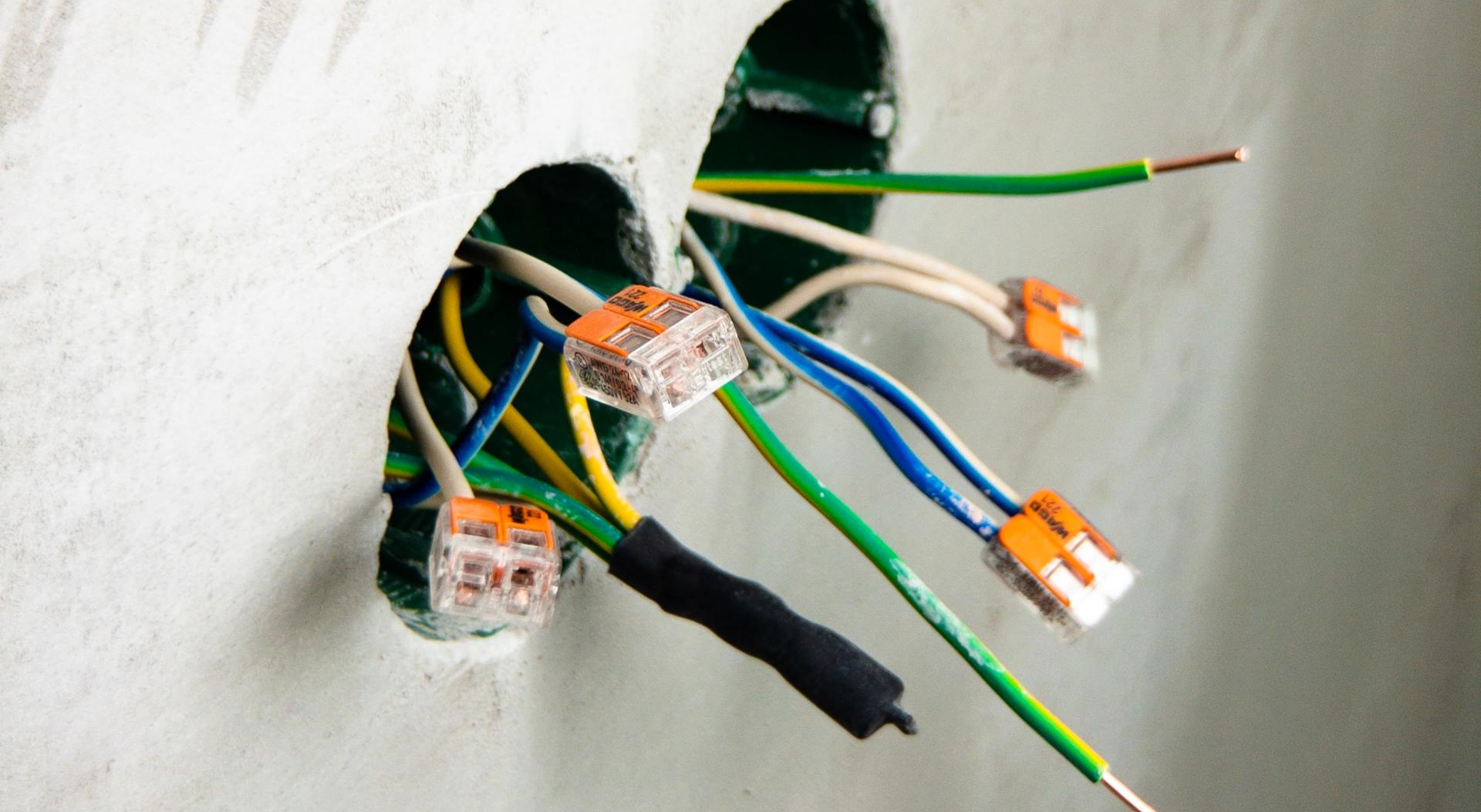 A bunch of wires are coming out of a hole in a wall.