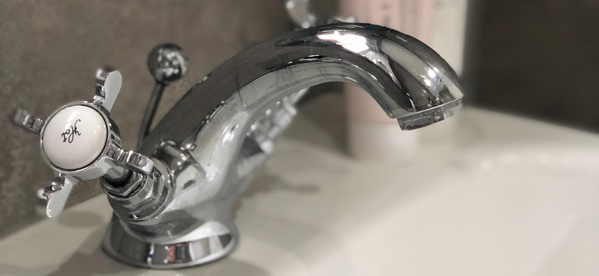 A close up of a bathroom sink faucet with a white handle.