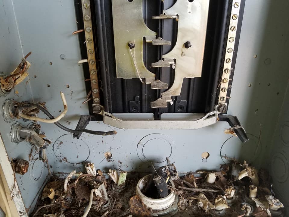 A dirty electrical box with a lot of wires coming out of it.