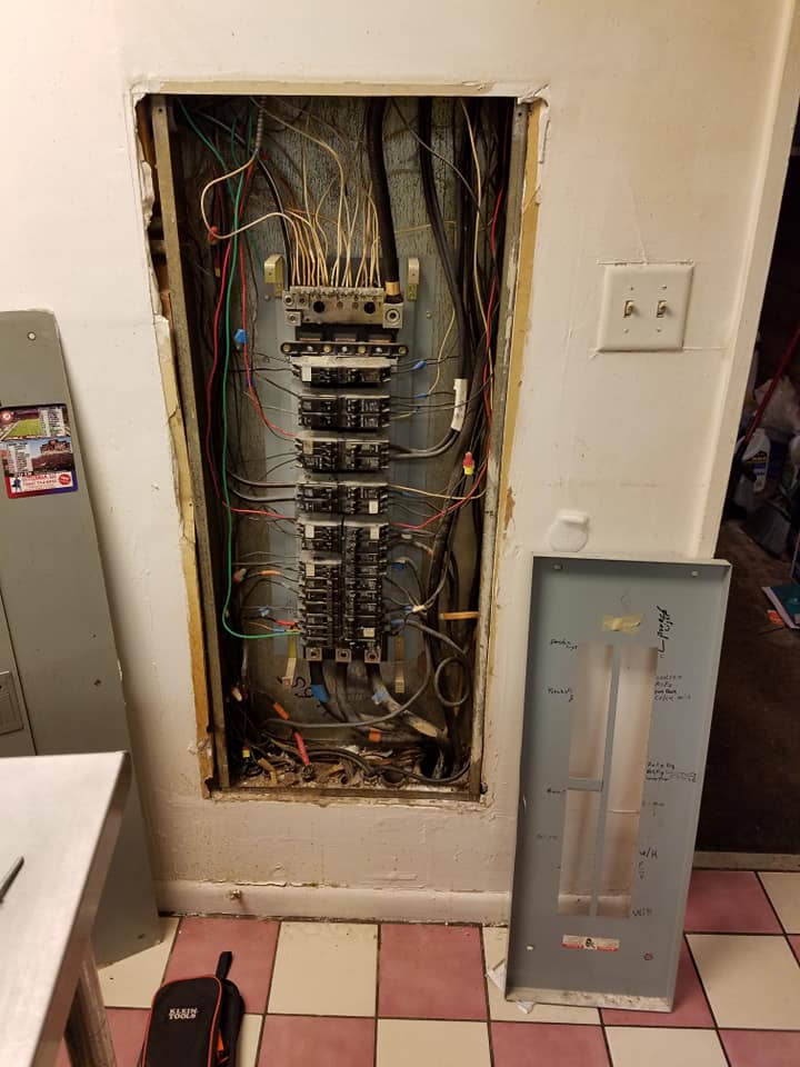A very old electrical panel is sitting on a tiled floor in a room.