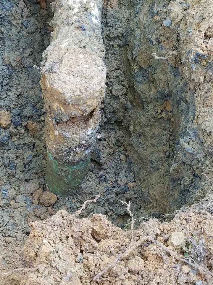 A pipe is laying in the dirt in a hole.