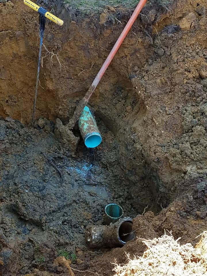 A blue pipe is sitting in the dirt next to a shovel.