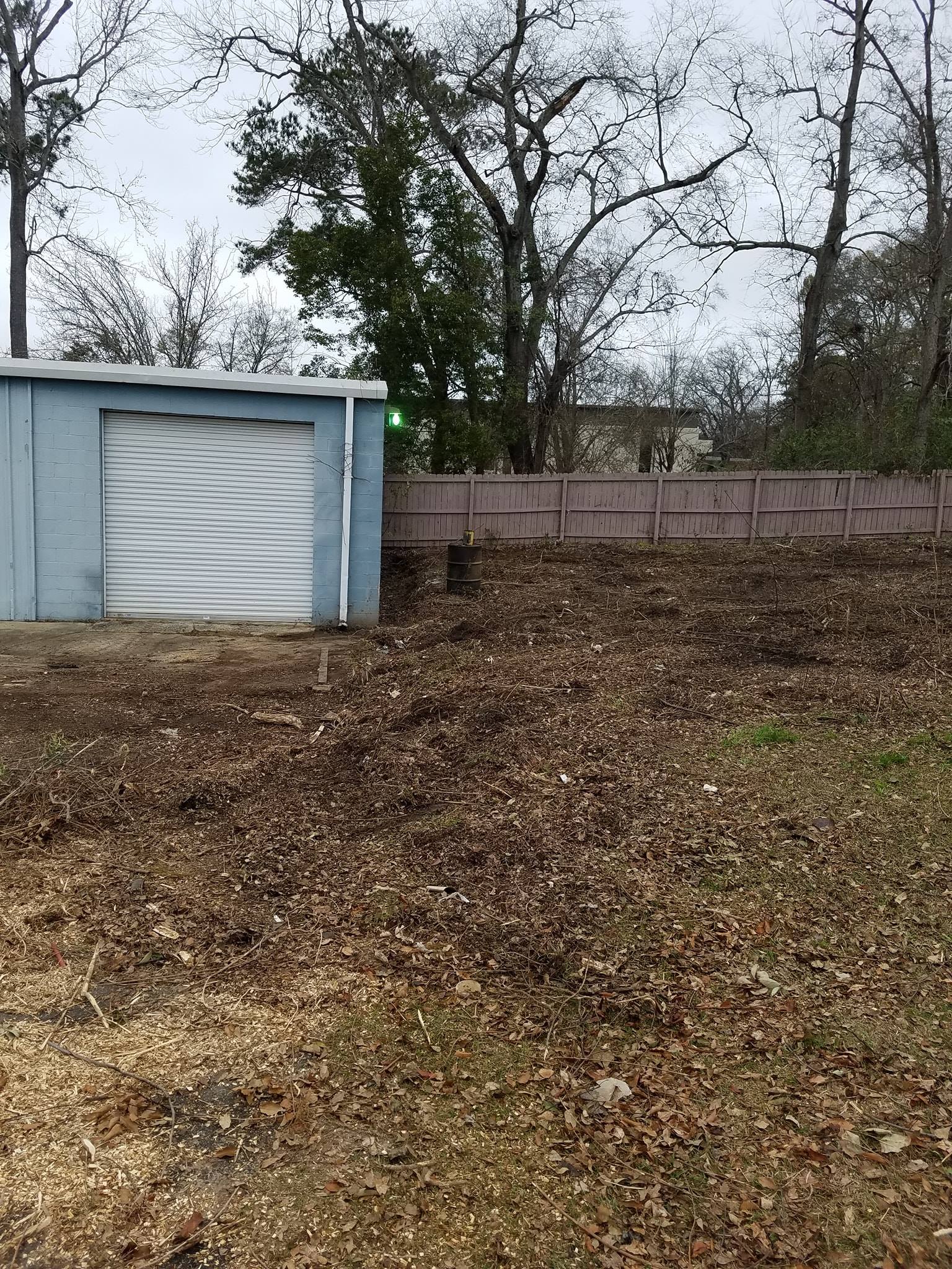 A blue garage with a white door is sitting on top of a dirt hill.