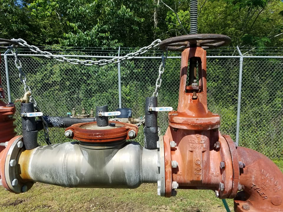 A fence with a bunch of pipes and valves attached to it