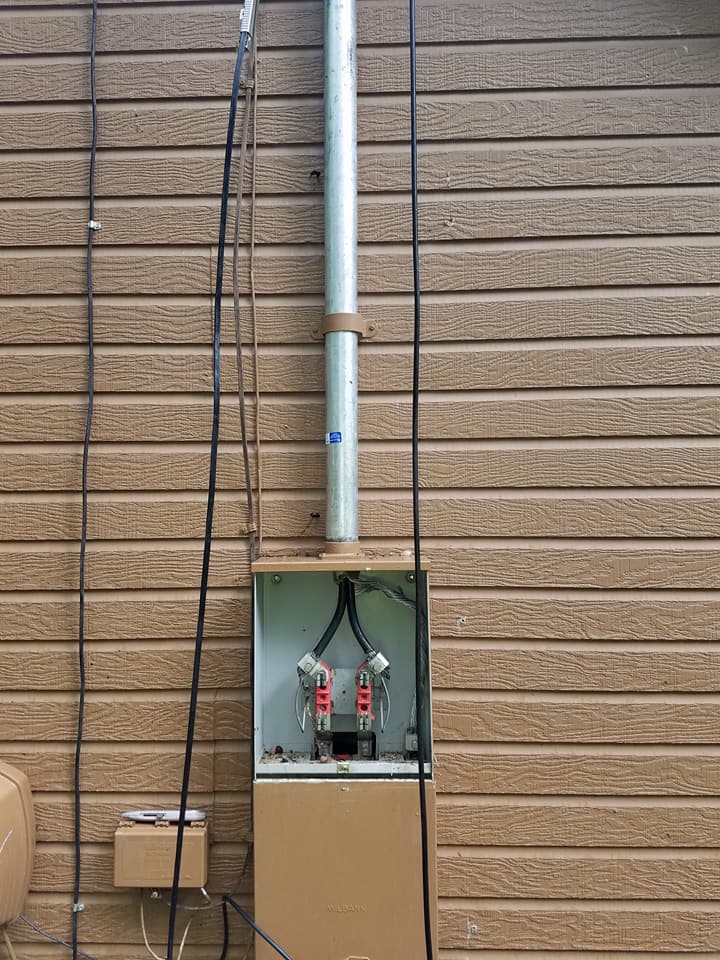 A box with a pipe coming out of it on the side of a building