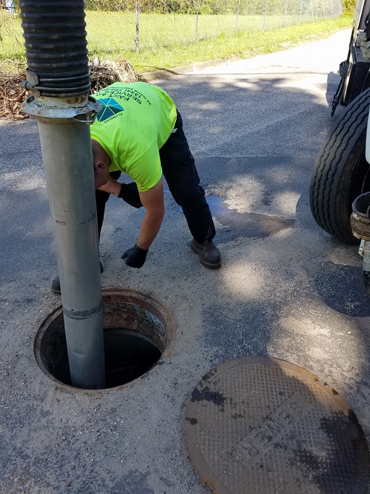 A man is working on a manhole cover next to a truck.