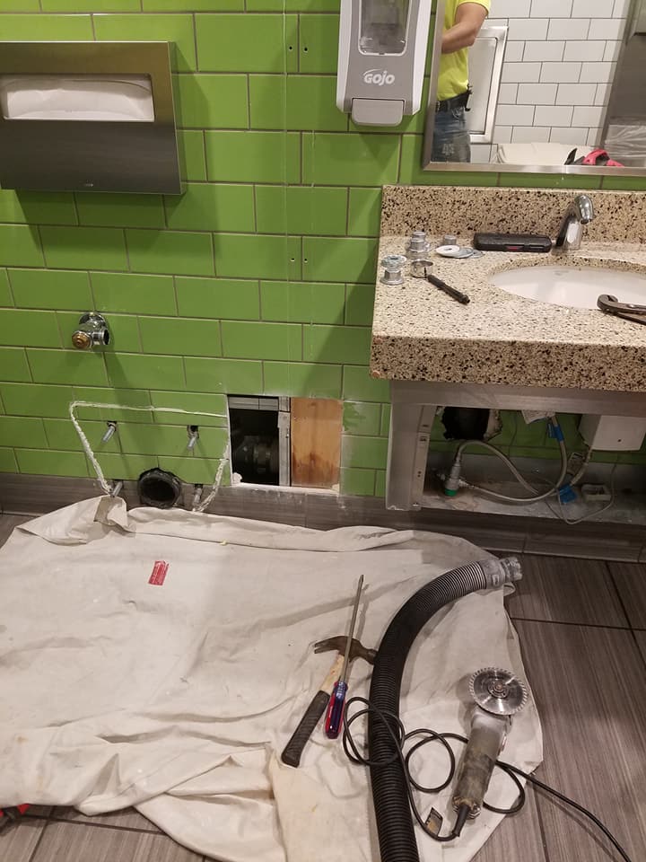 A bathroom with green tiles and a sink is being remodeled.