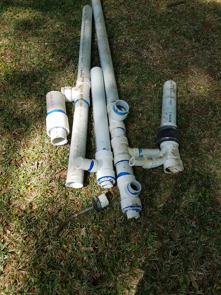 A bunch of white pipes are laying on the grass.