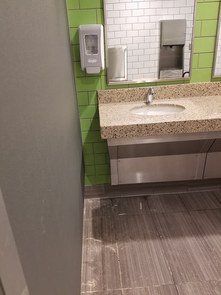 A bathroom with a sink , mirror and soap dispenser.