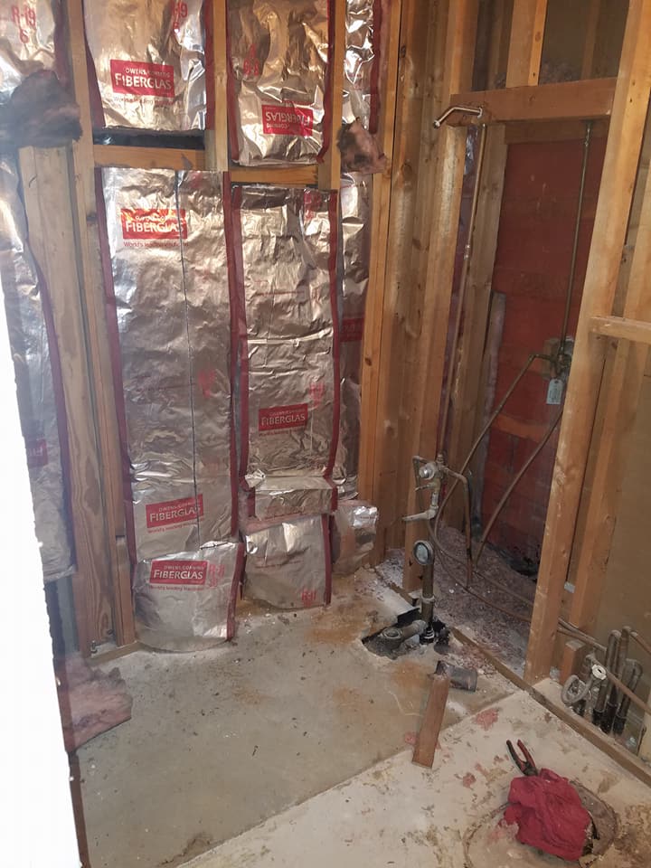 A bathroom under construction with aluminum foil on the walls.