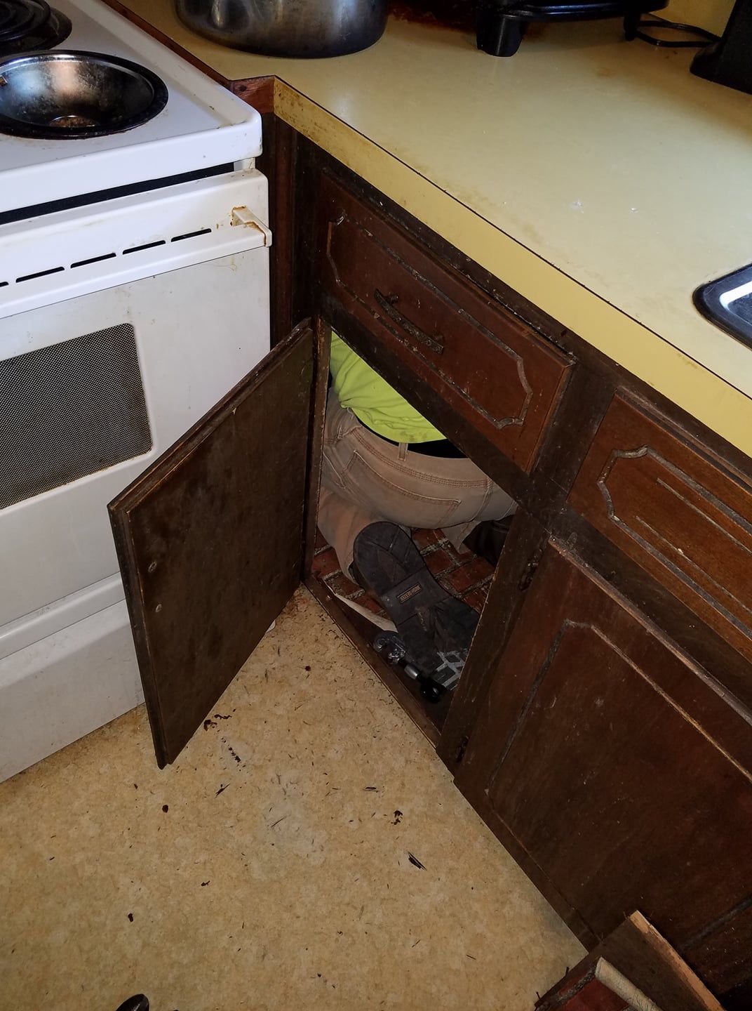 A kitchen with a stove and a drawer with clothes in it