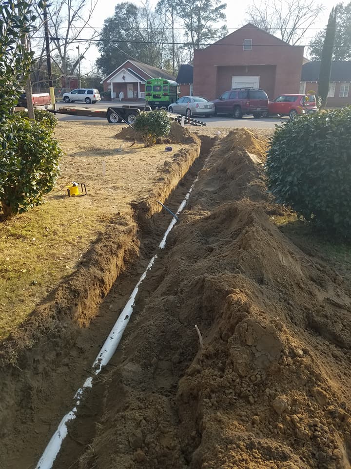 A pipe is being installed in the dirt in front of a building