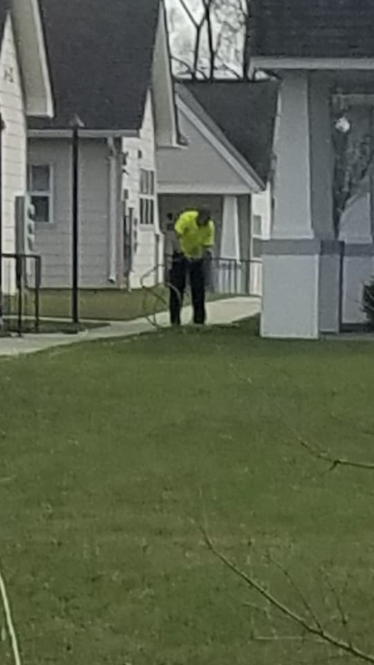 A man is standing on a lush green lawn in front of a house.