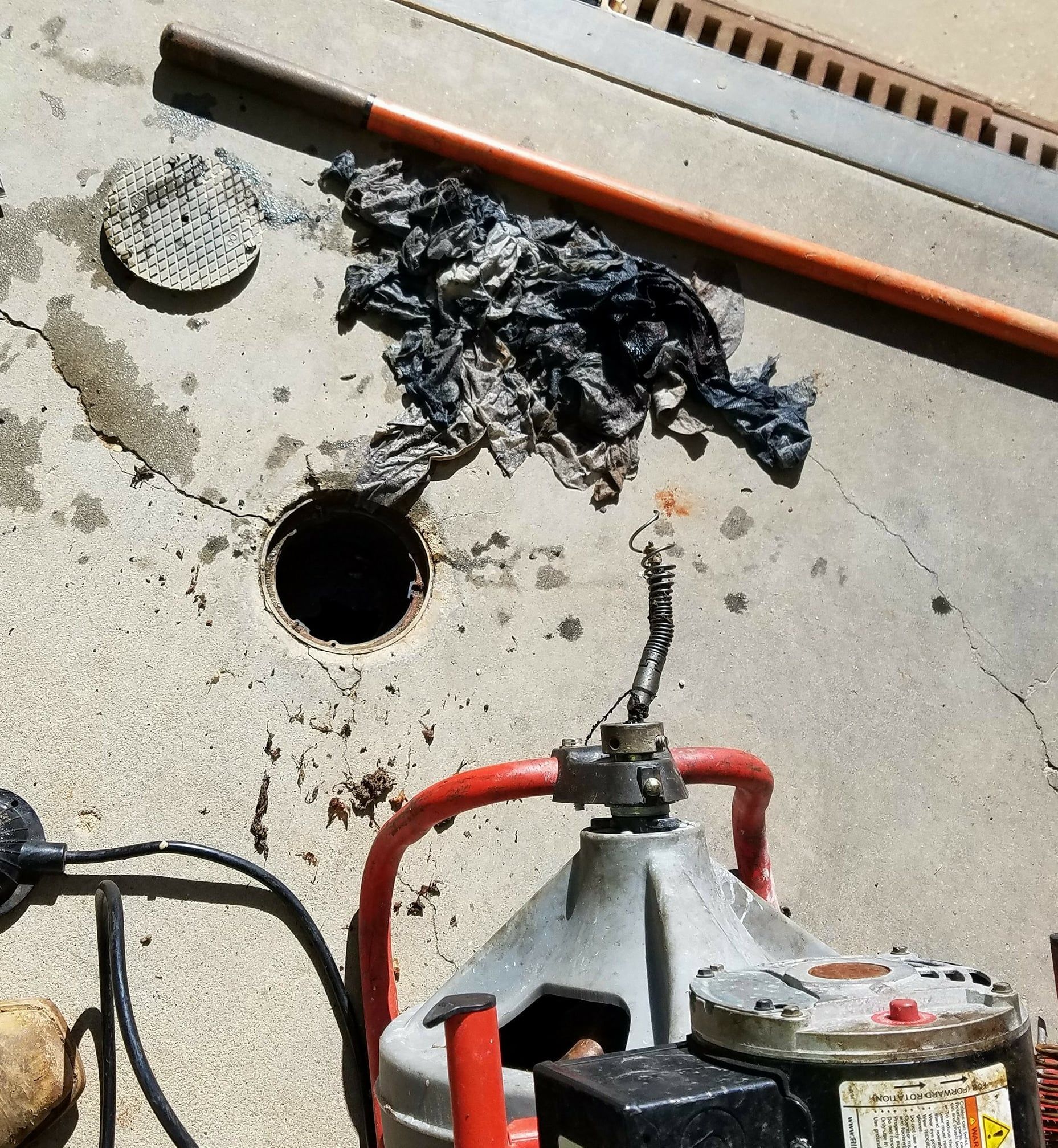 A drain cleaner is sitting next to a hole in the ground