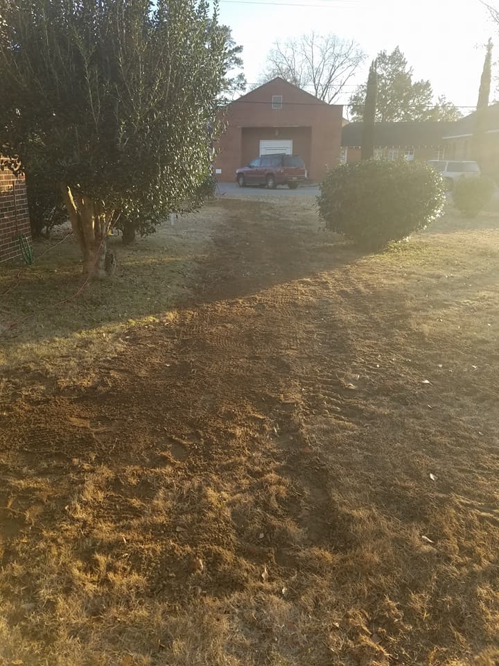 A red truck is parked in a driveway next to a brick building.