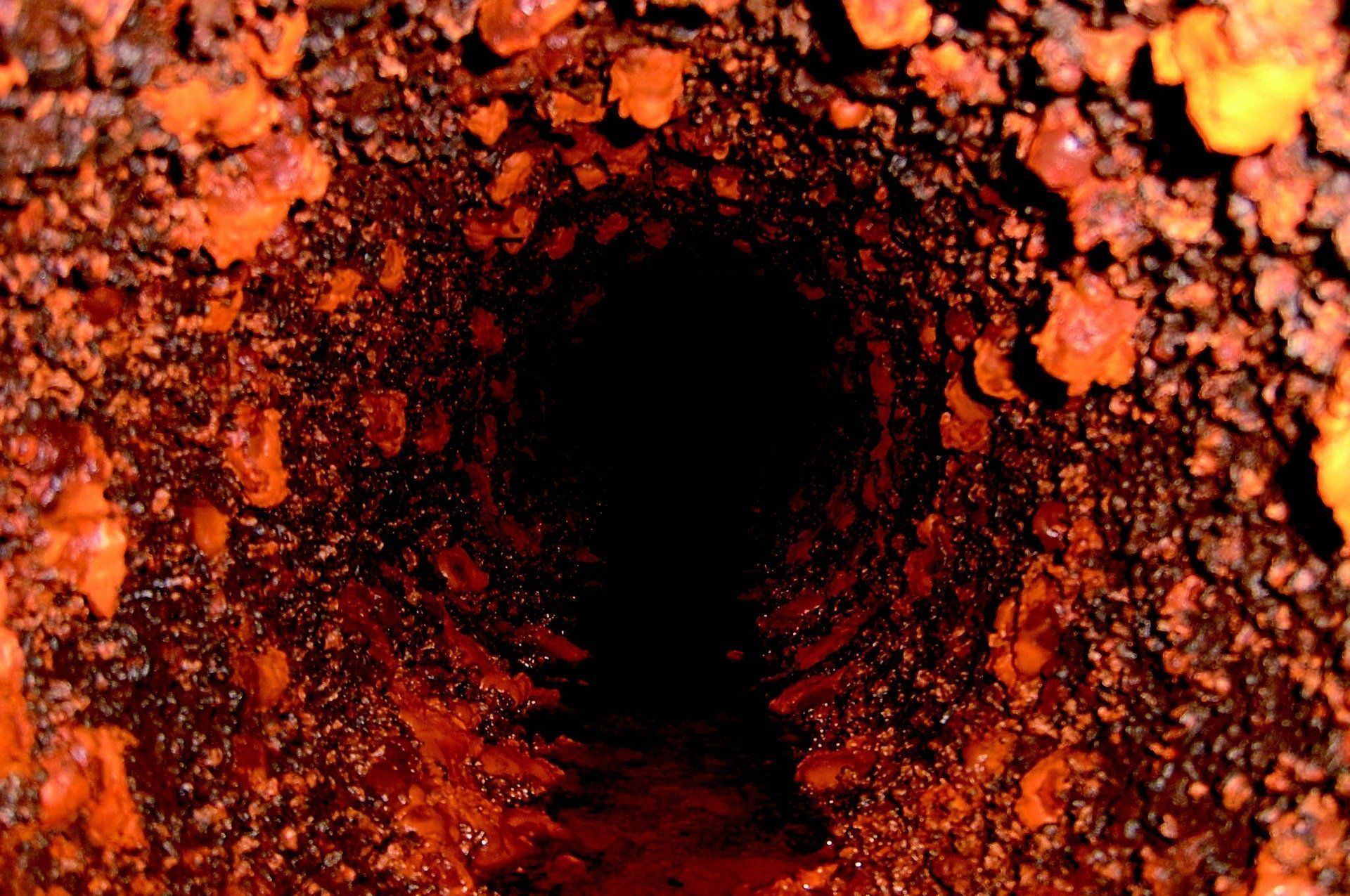 Dark tunnel or cave opening surrounded by glowing orange-red rocky texture