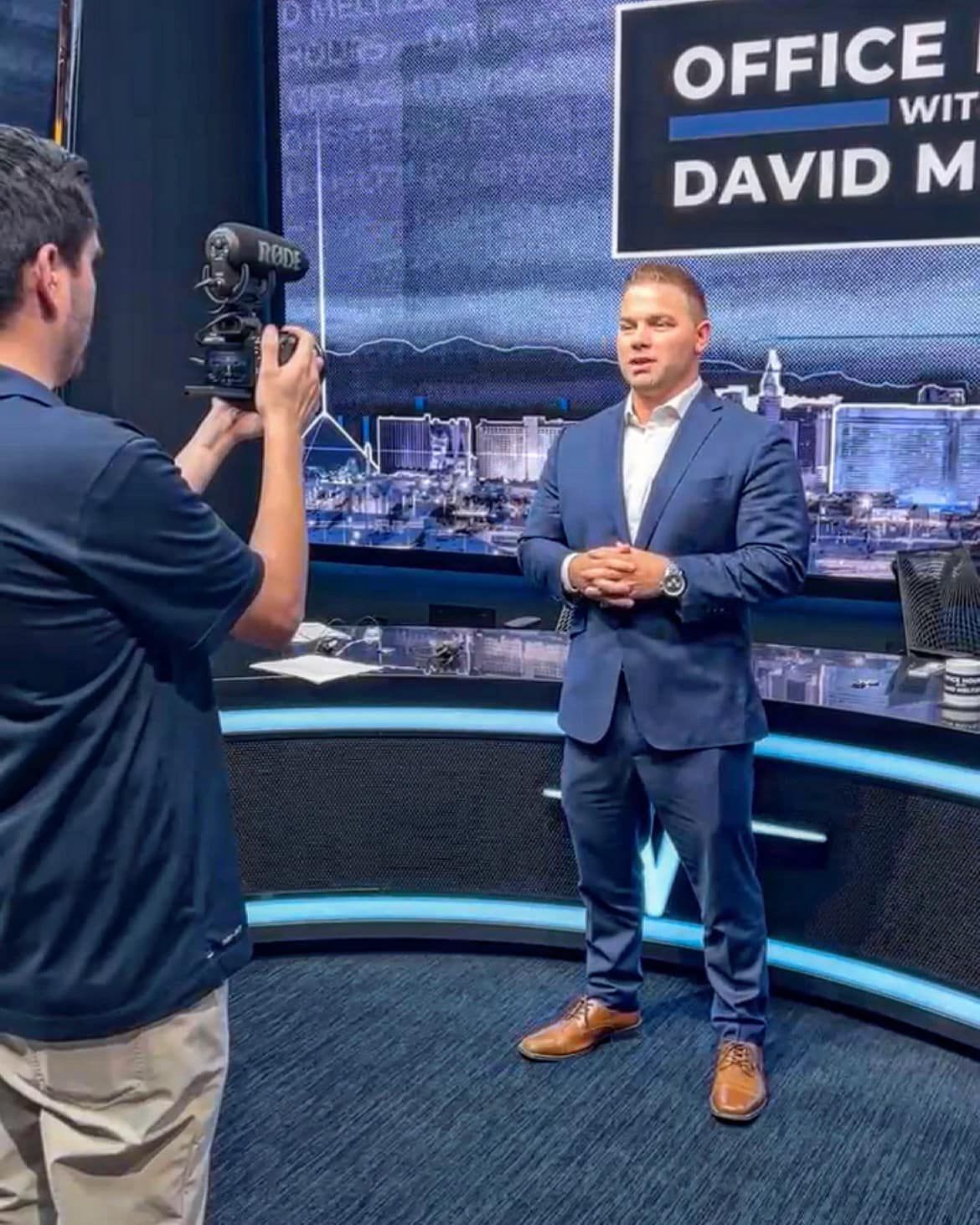 A man in a suit is standing in front of a sign that says office with david