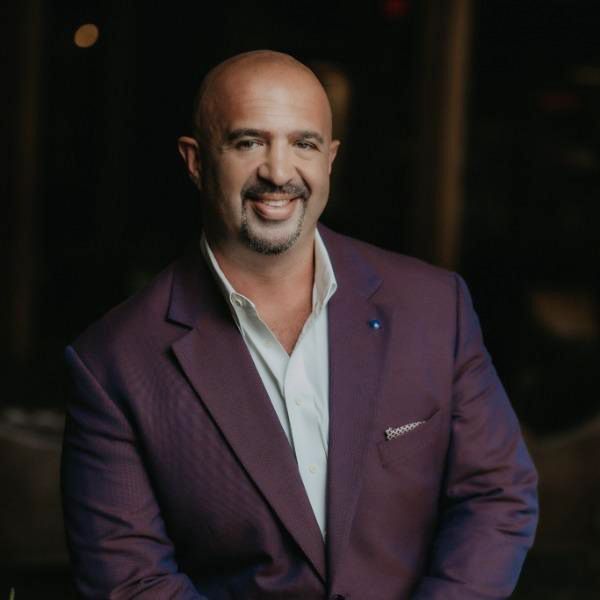 A man in a purple suit is smiling for the camera