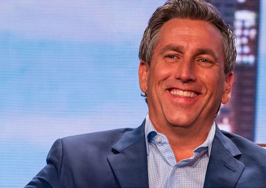 A man in a suit is smiling and looking at the camera.