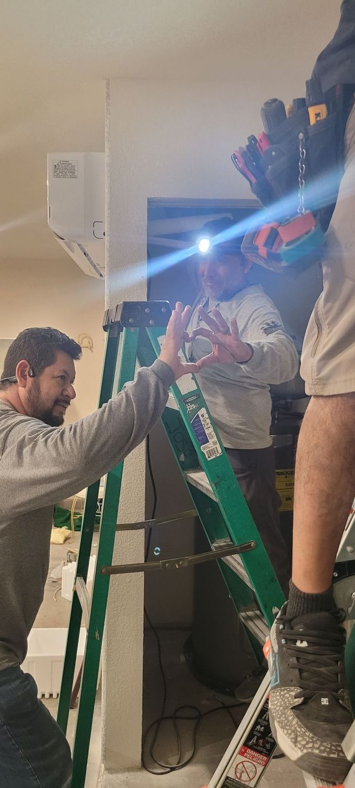 A man in a blue shirt is working on a ceiling fan
