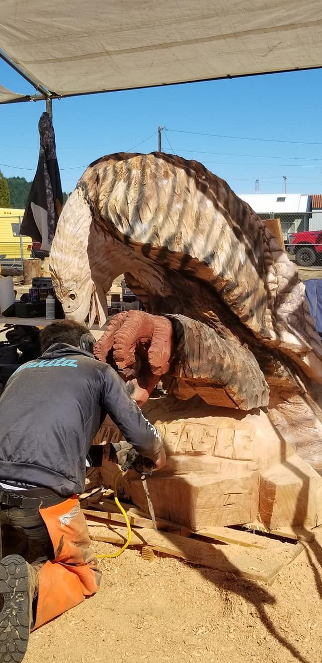 A man is kneeling down in front of a large piece of wood.
