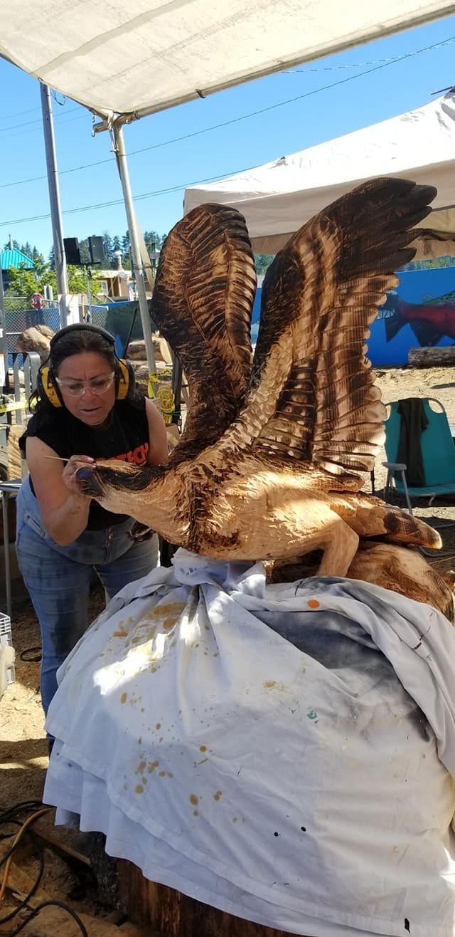 A woman is carving an eagle out of wood.