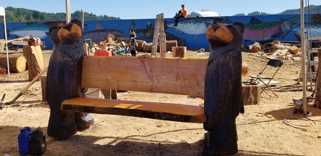 Two carved bears are sitting on a wooden bench.