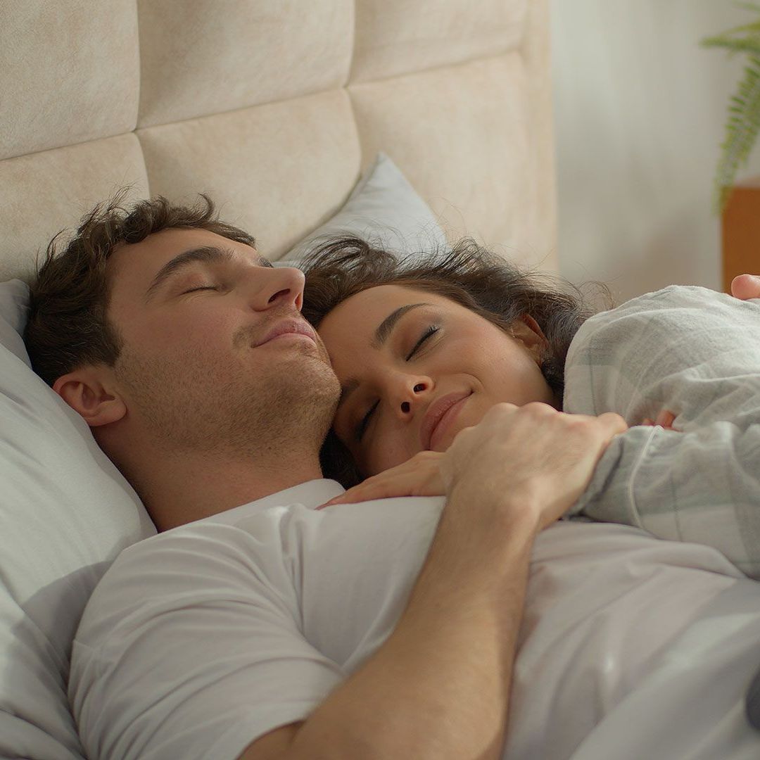 A man and a woman are sleeping next to each other in a bed.