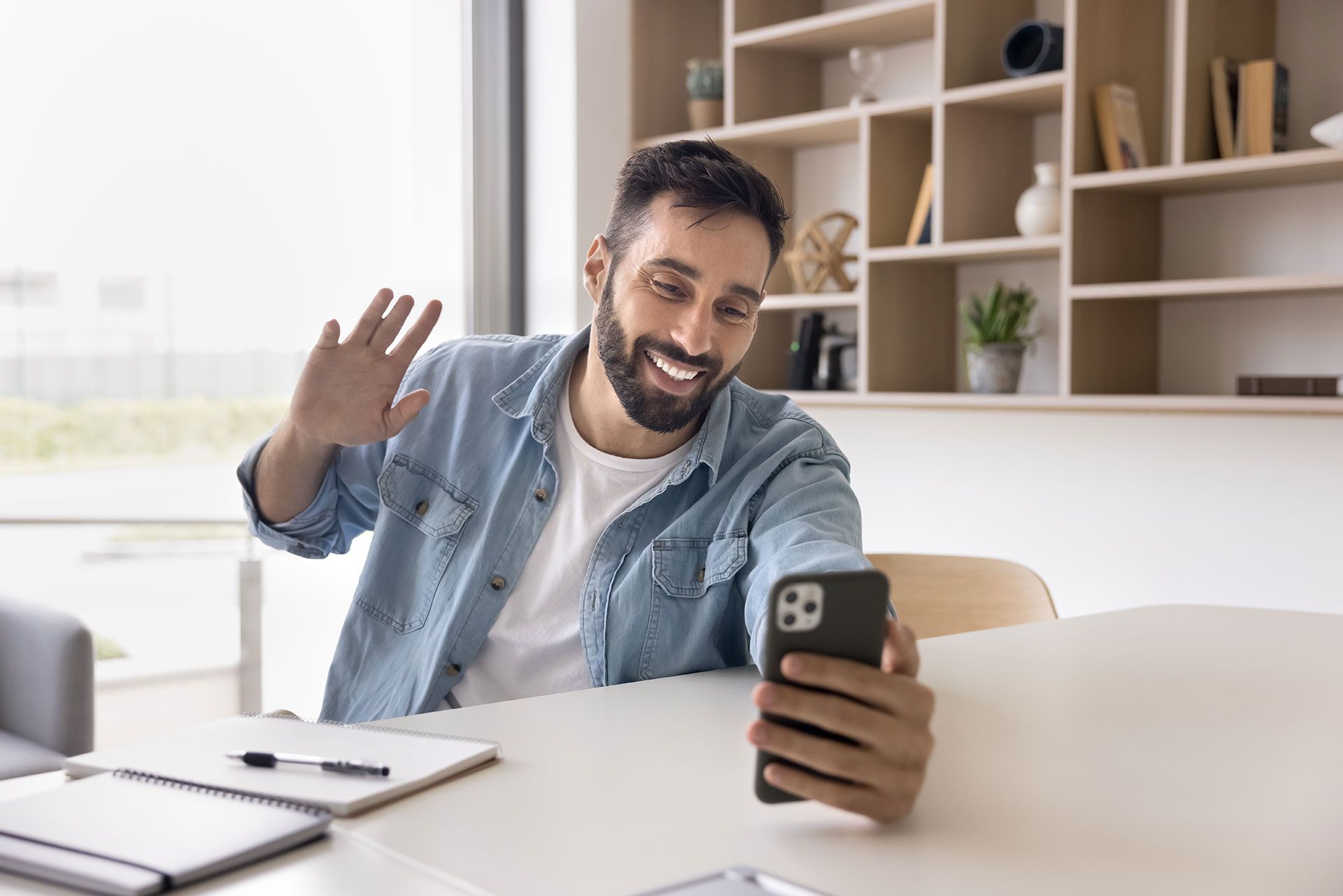 A man is sitting at a table using a cell phone.