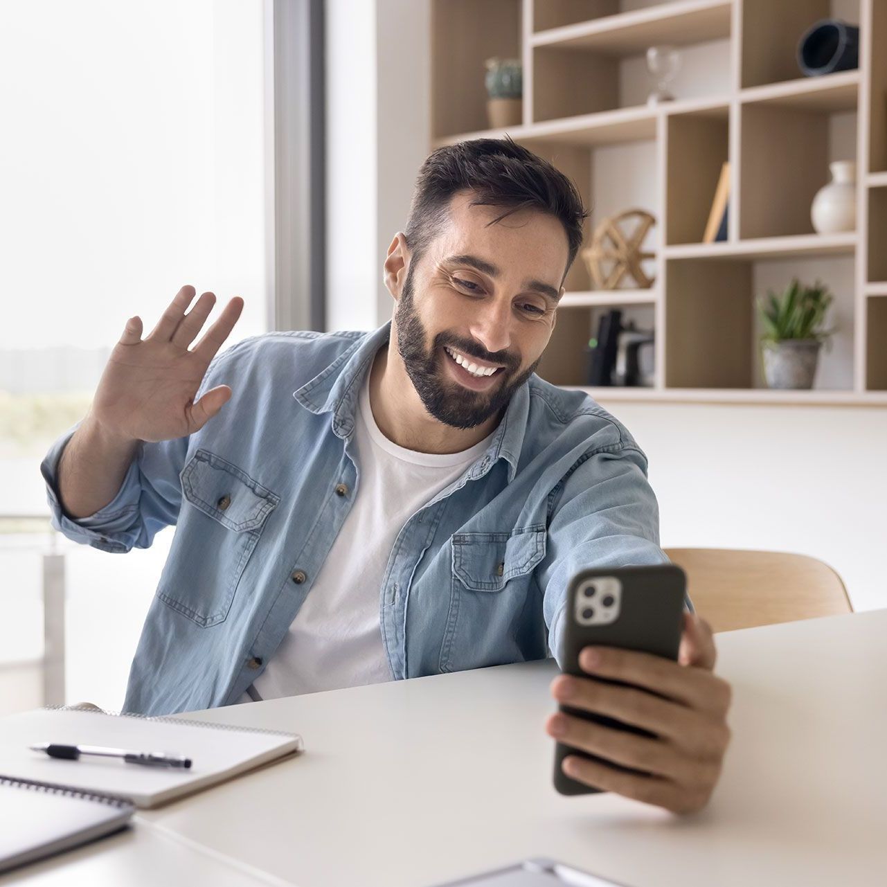 A man is sitting at a table looking at his cell phone.