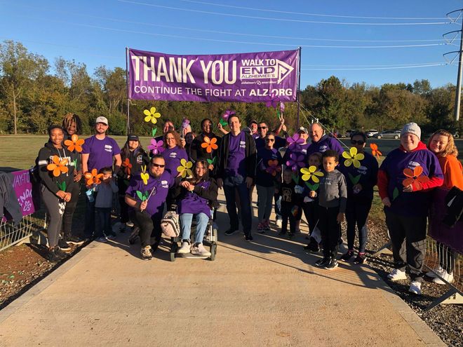 A group of people are standing in front of a thank you sign.