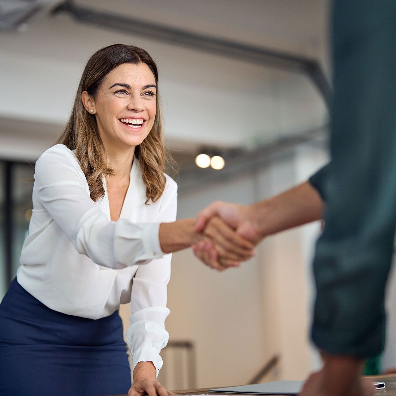 A woman is shaking hands with a man in an office.