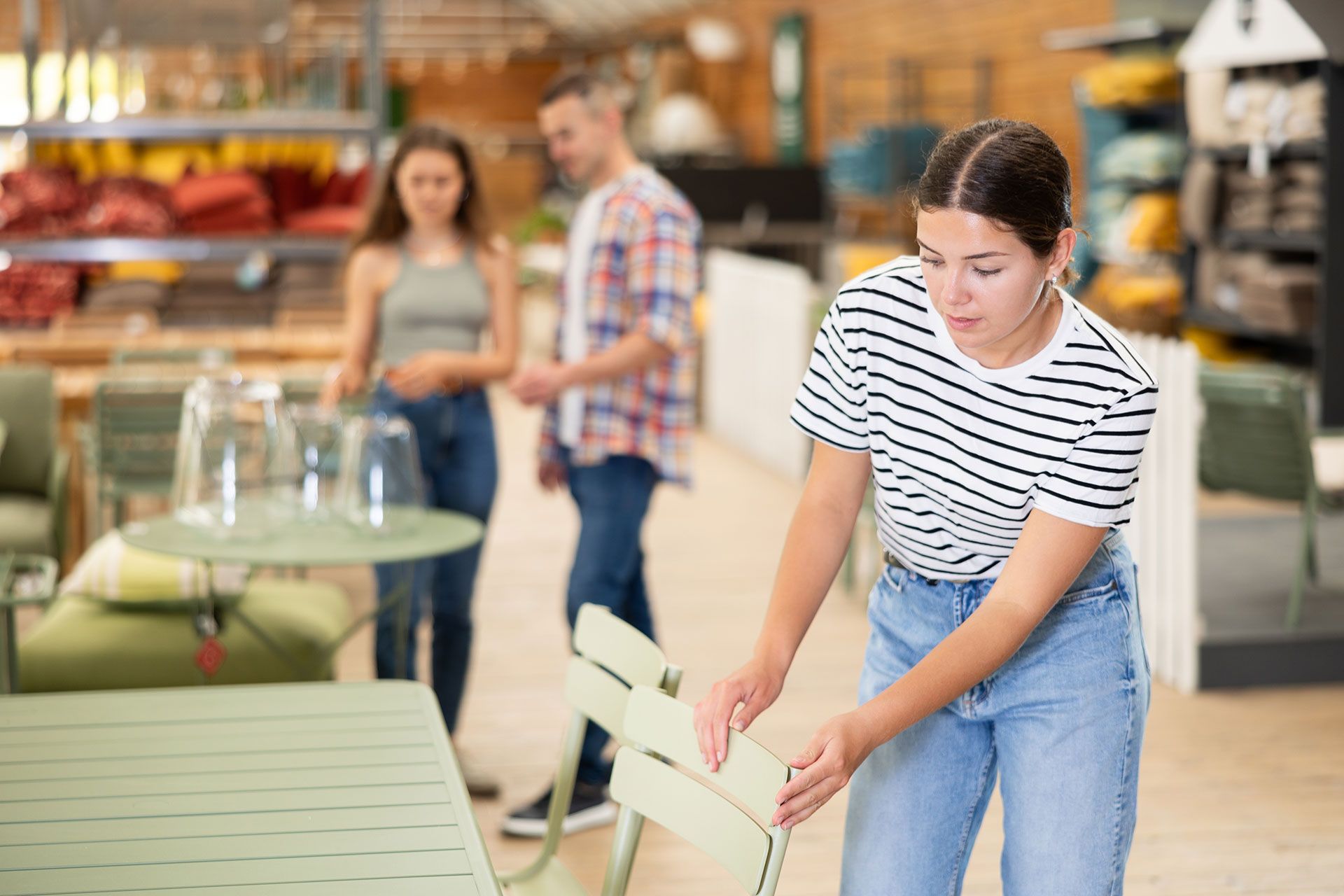 A woman is putting a chair on a table in a store.