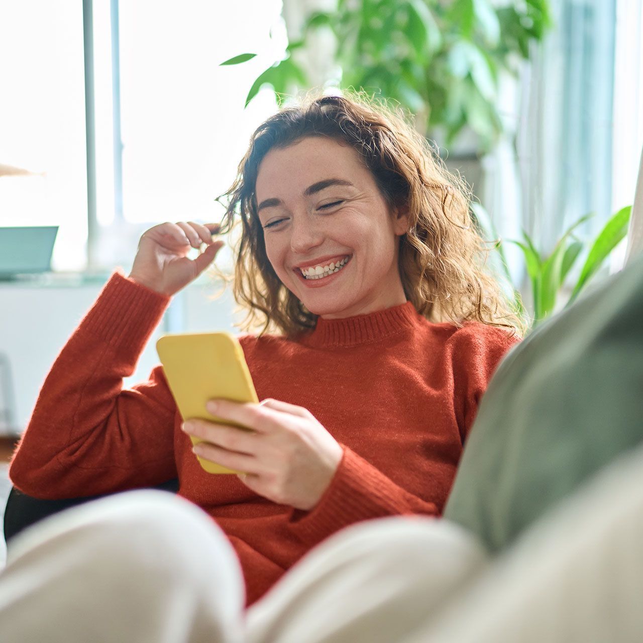 A woman is sitting on a couch looking at her cell phone.