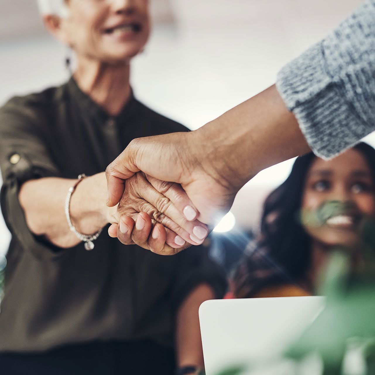 A man and a woman are shaking hands in an office.