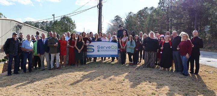 A large group of people are standing in front of a sign.