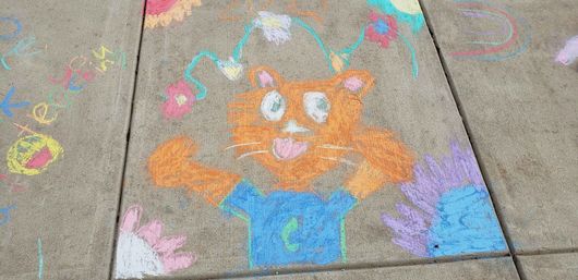 A chalk drawing of a cat in a hat on a sidewalk.