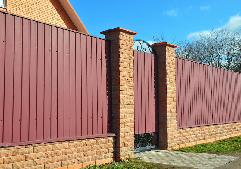 A Brick Fence With A Red Fence And A Gate In Front Of A Brick House — A Betta Fence 'N' Yard In Port Macquarie, NSW