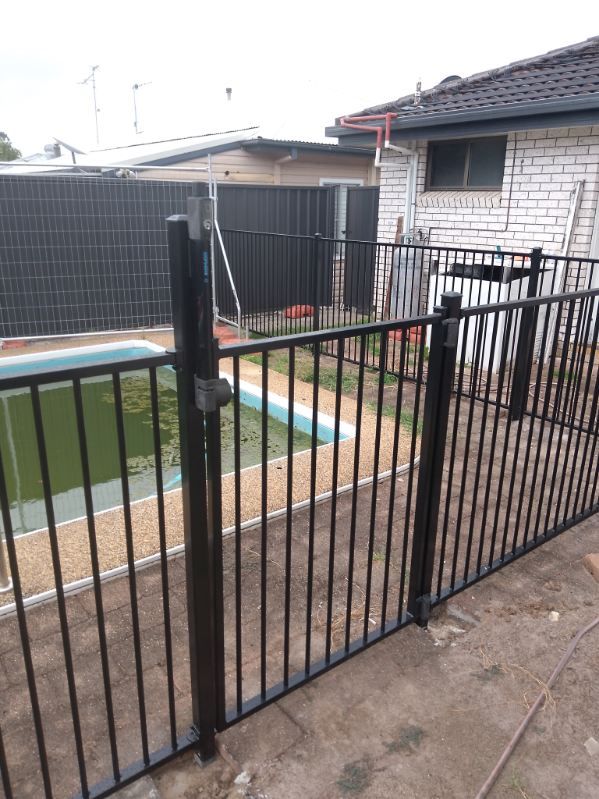 A Black Metal Fence Surrounds A Swimming Pool In A Backyard — A Betta Fence 'N' Yard In Port Macquarie, NSW