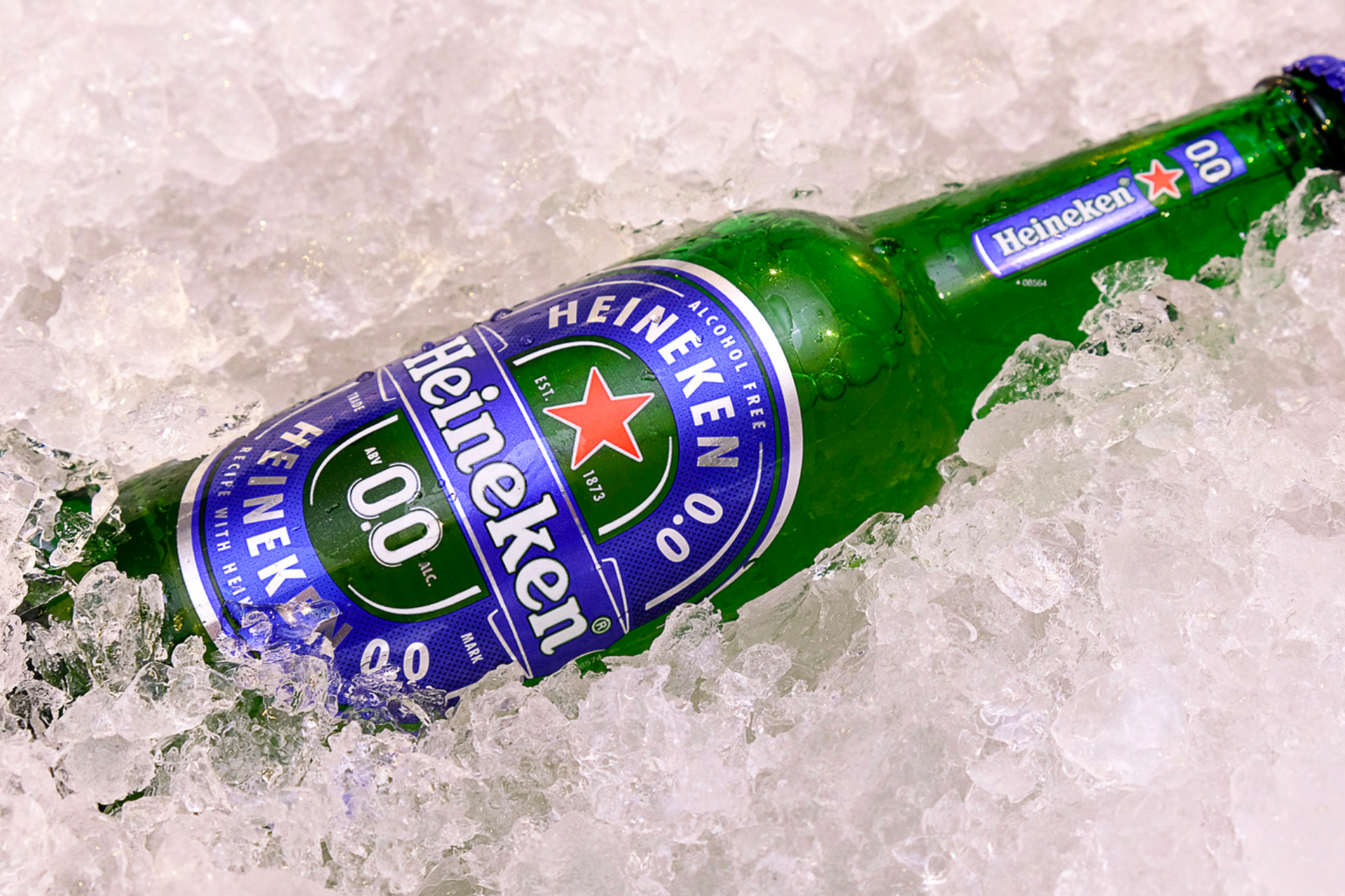 A bottle of heineken beer is sitting on ice