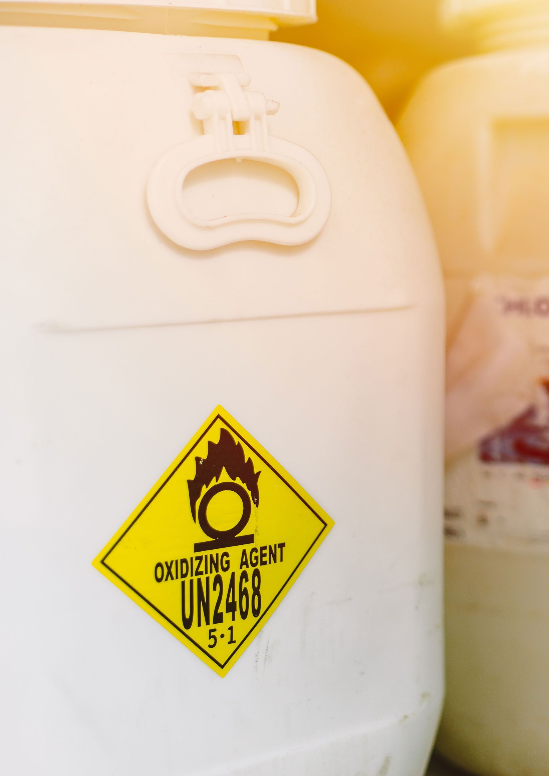 White chemical drum with yellow oxidizing agent hazard label, UN2468.