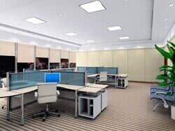 Un interior de oficina limpio y moderno con filas de escritorios, mamparas para mayor privacidad, sillas de oficina y una planta en maceta.