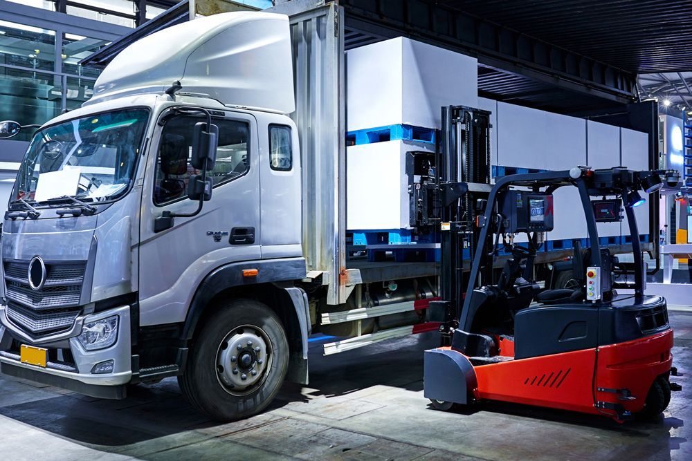 A truck is parked next to a forklift in a warehouse.