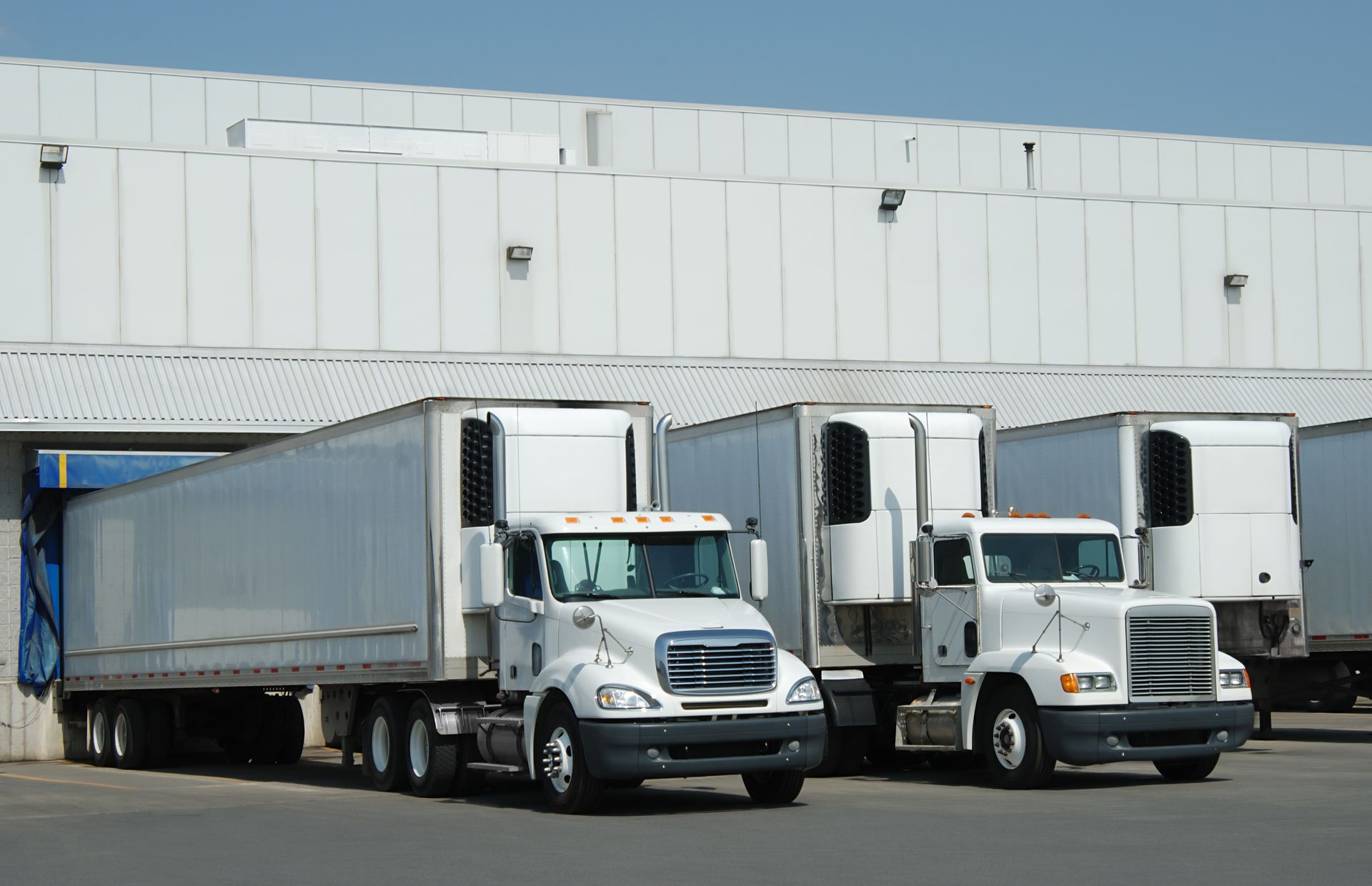 A row of semi trucks are parked in front of a building.