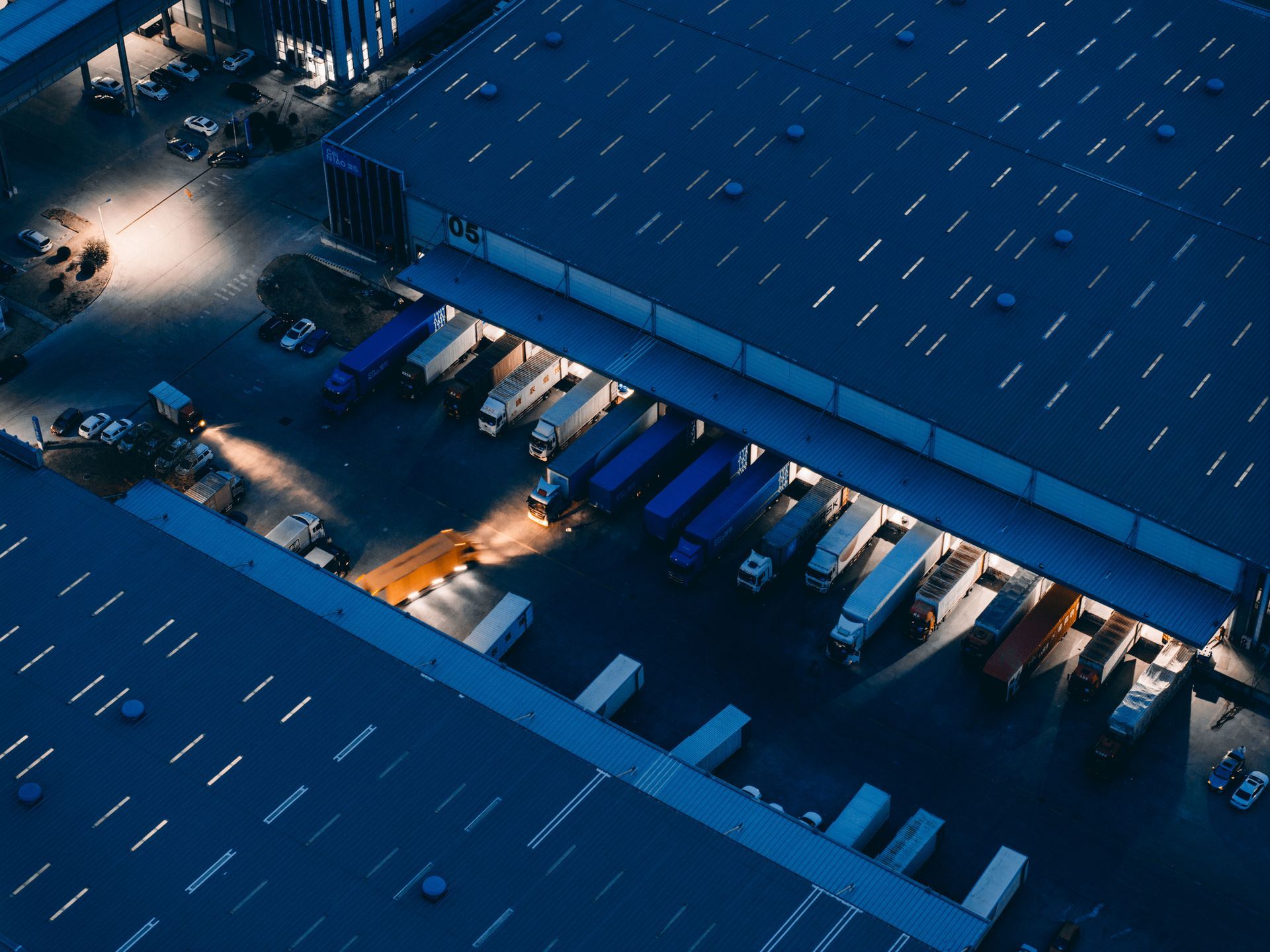 An aerial view of a warehouse with trucks parked in front of it at night.