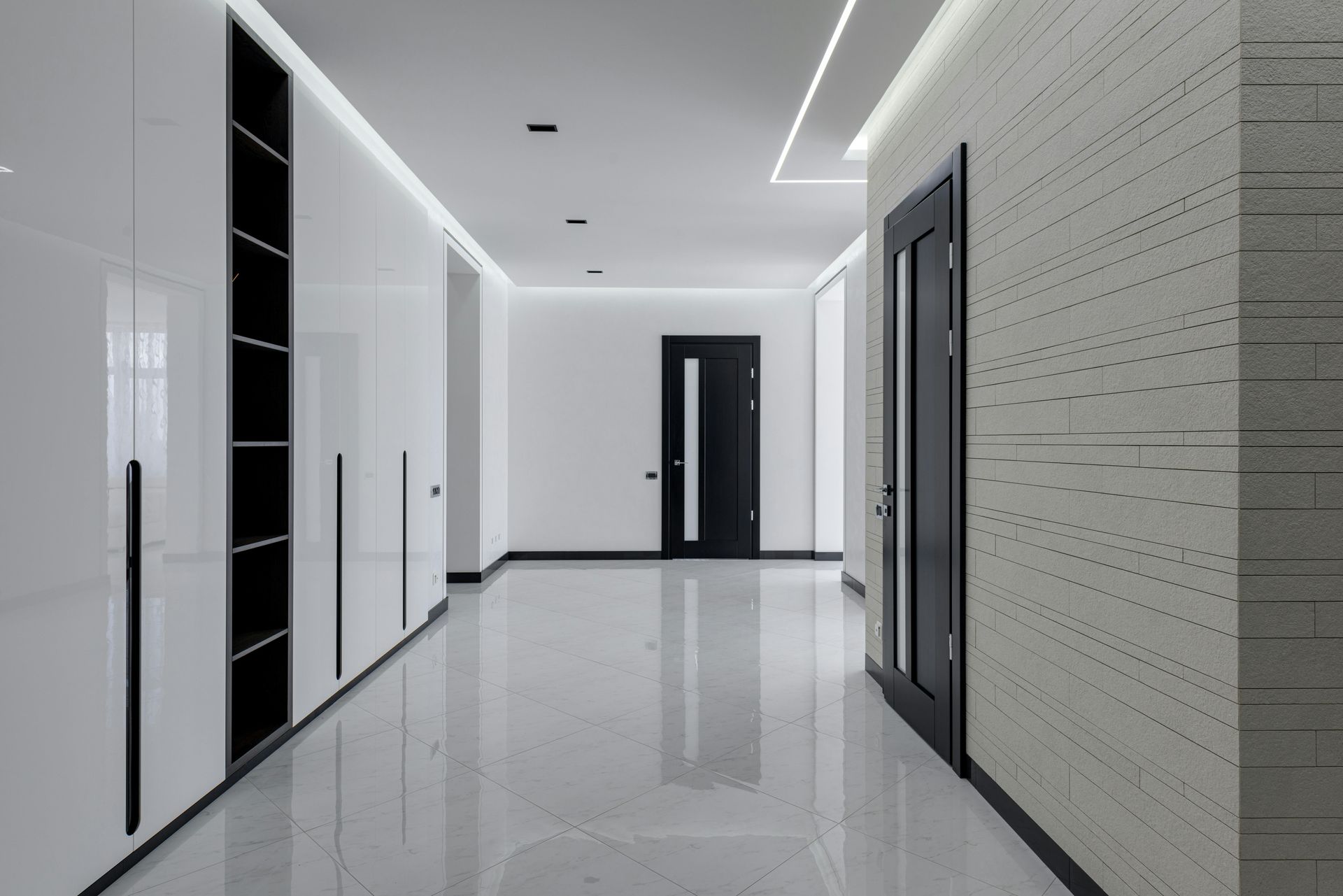 Modern hallway with white cabinets, dark doors, and reflective flooring.