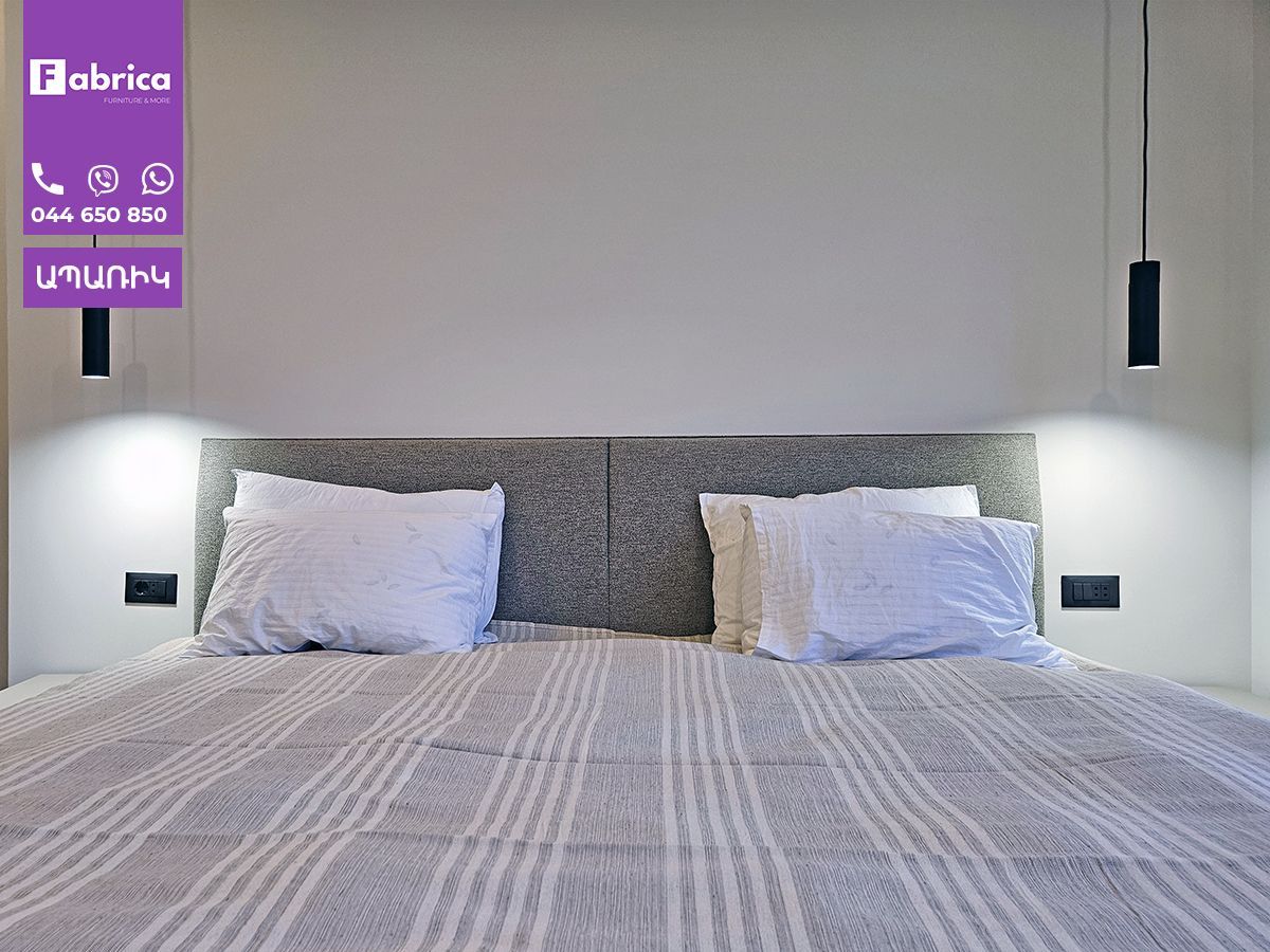 A bed with a striped blanket and white pillows in a bedroom.