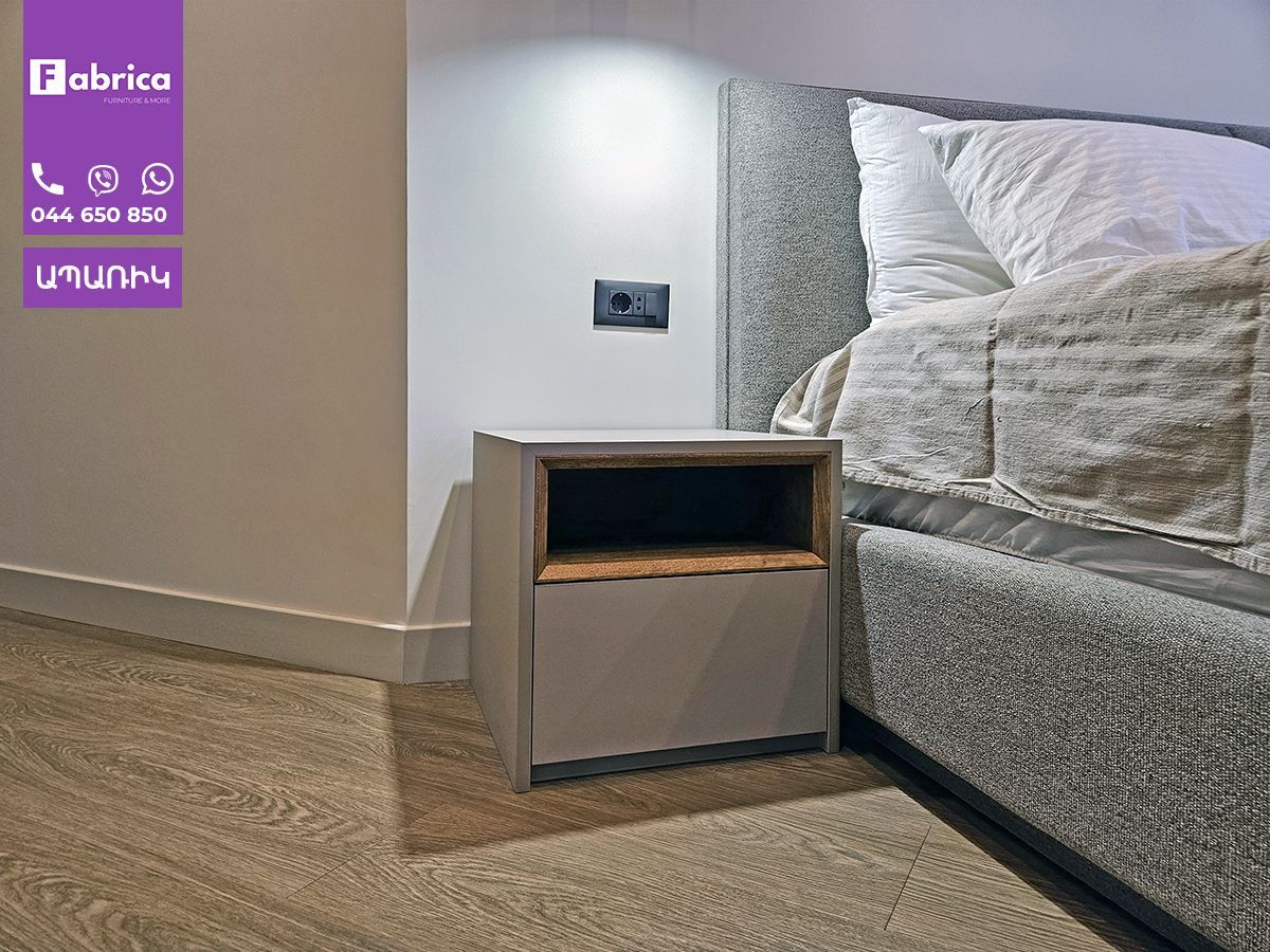 A bed with a nightstand next to it in a bedroom.