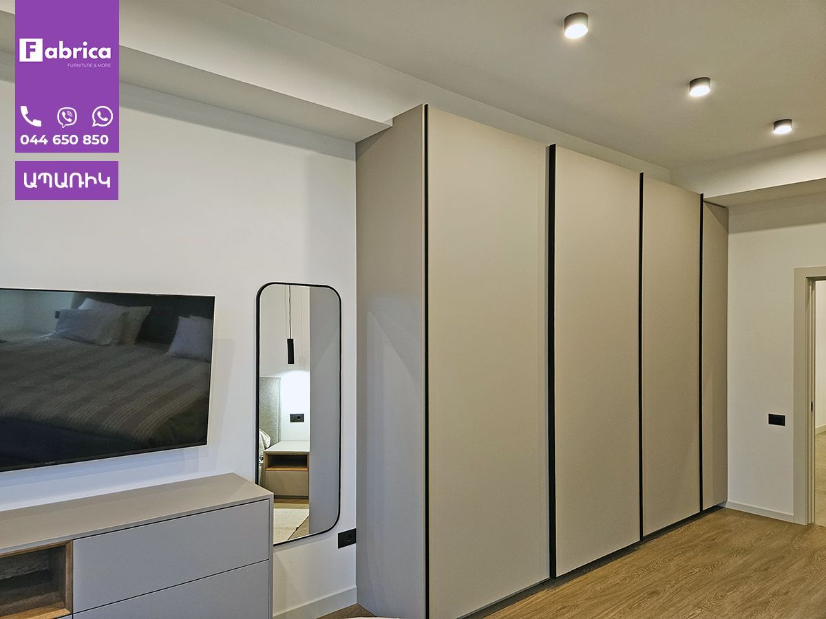 A bedroom with a large wardrobe and a flat screen tv